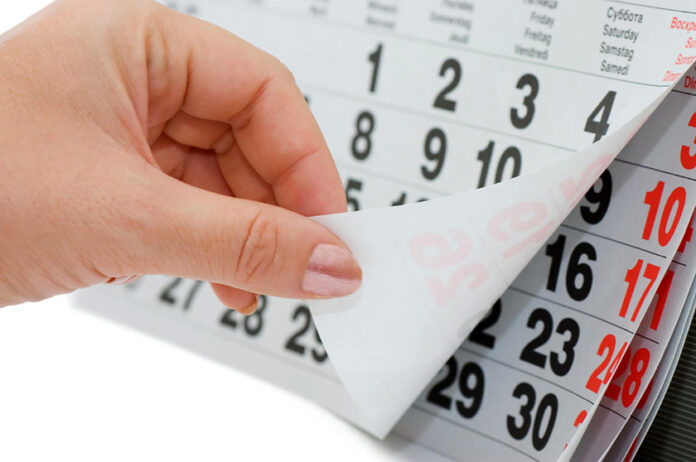 The hand overturns calendar sheet isolated on white background